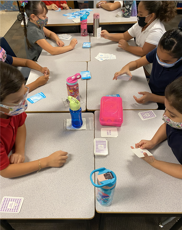 Students playing a math game with cards in a classroom